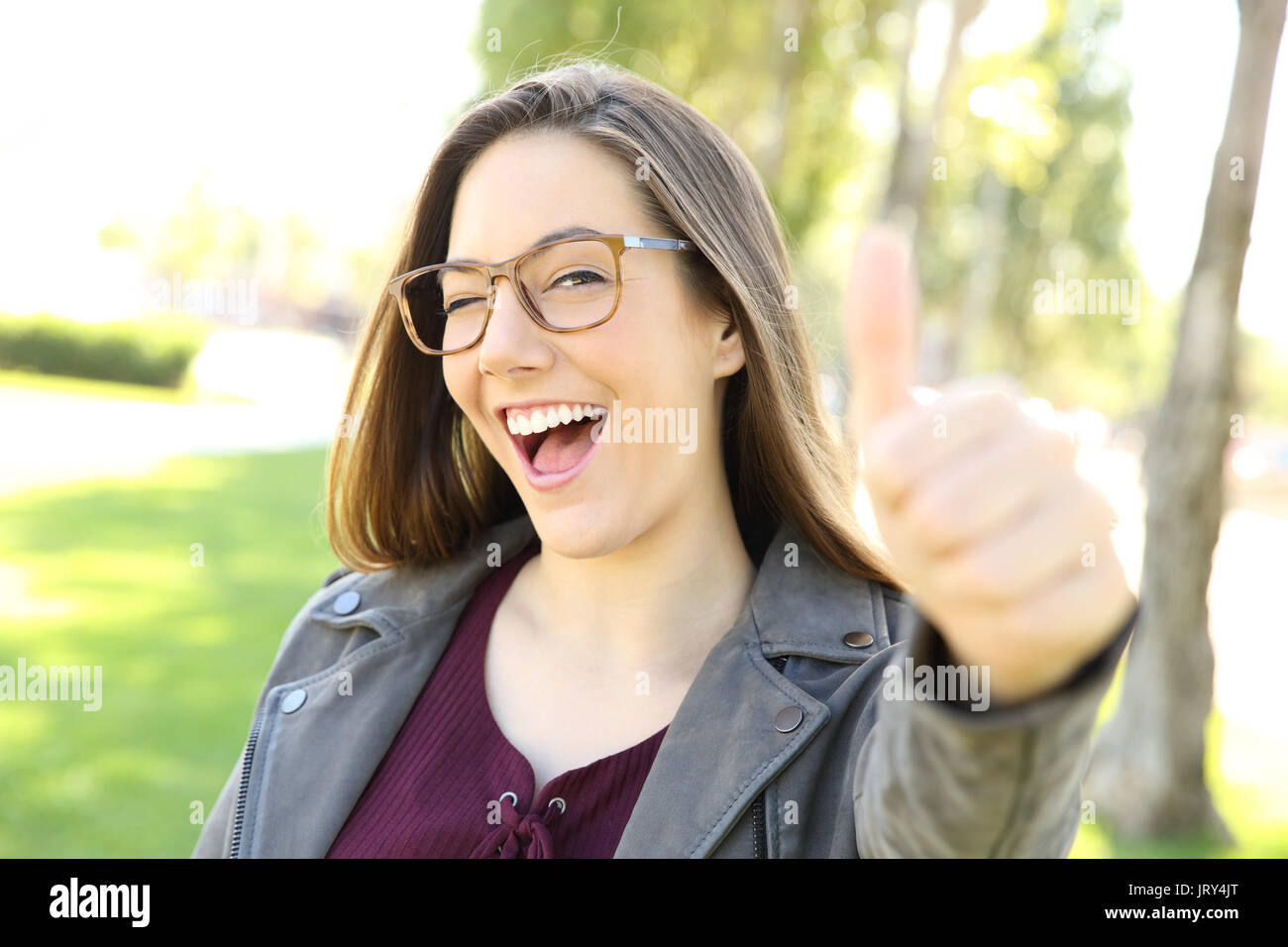 Porträt einer lustig Mädchen tragen Brillen Gestik Daumen nach oben und betrachten sie in einem Park im Freien Stockfoto
