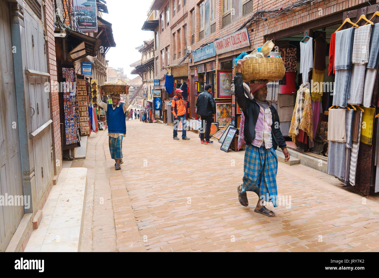 Männer und Merchandise in Körben auf dem Kopf statt. Bhaktapur, Nepal. Stockfoto