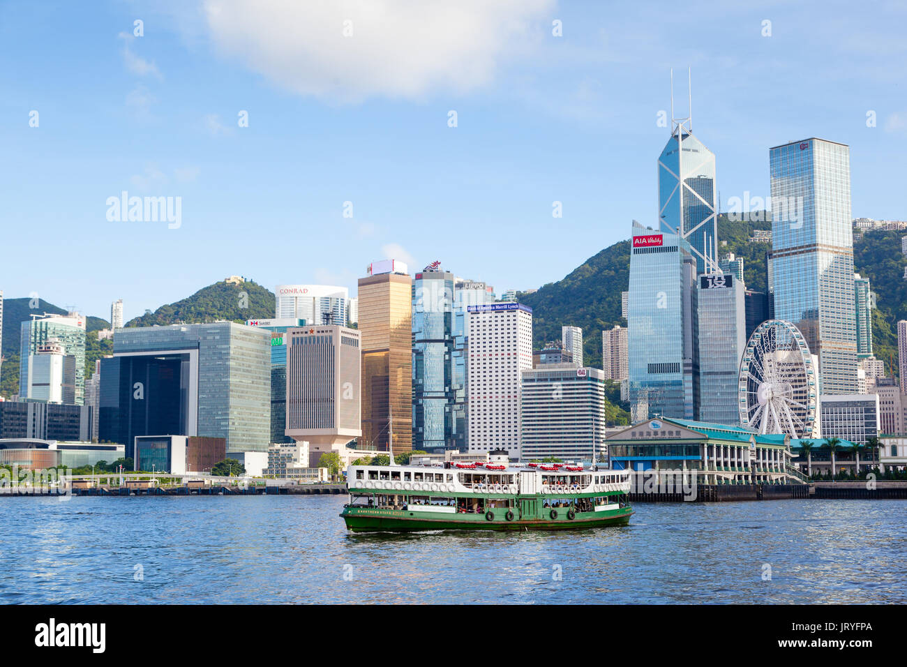 Eine Fähre bringt den Victoria Harbour in Tsim Sha Tsui, Hong Kong, mit der modernen Wolkenkratzer des Central District im Hintergrund auftauchen. Stockfoto