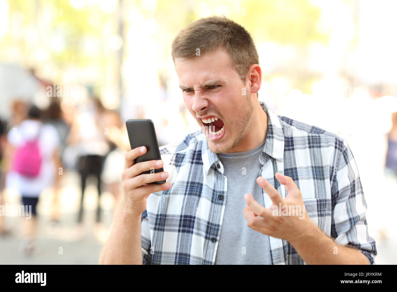 Zornigen mann Holding abgestürzt Handy auf der Straße Stockfoto