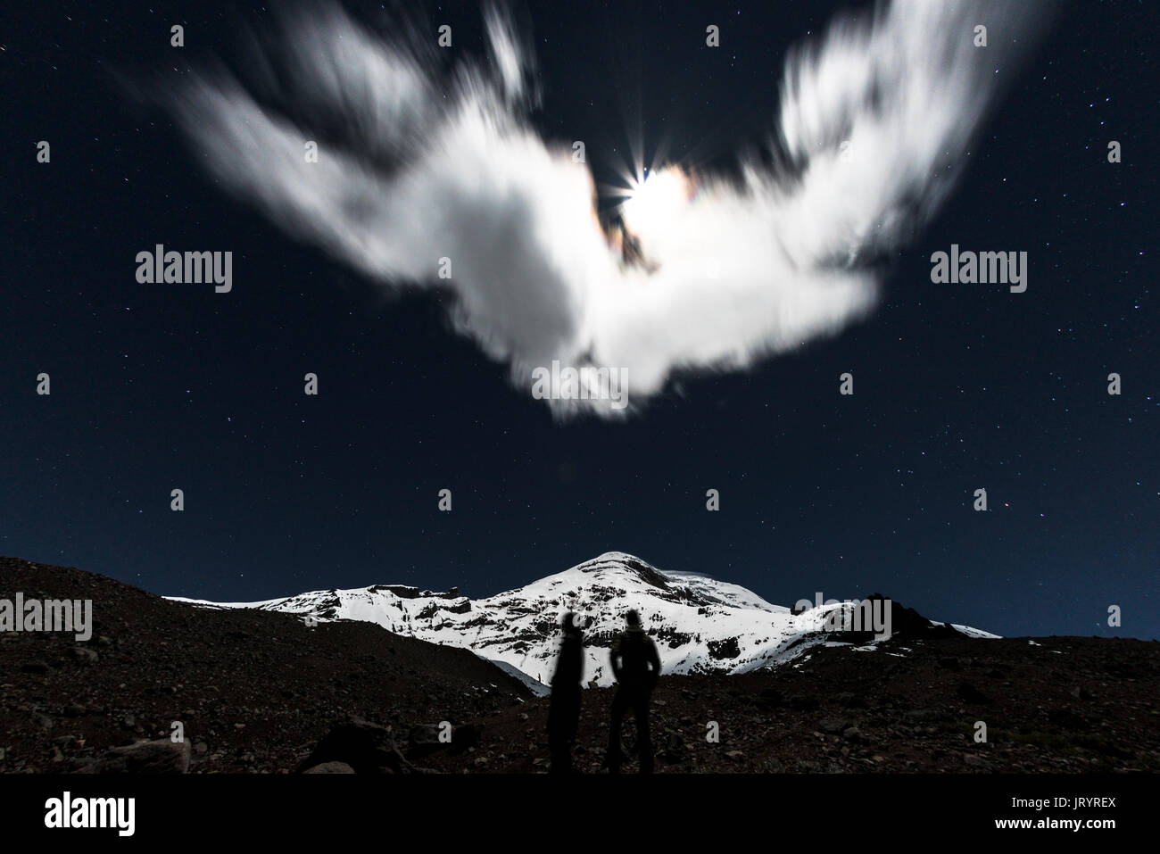 Zwei Silhouetten von ein paar stehen unter einem Vollmond schauen oben am Berg Chimborazo, der höchste Gipfel in Ecuador. Stockfoto
