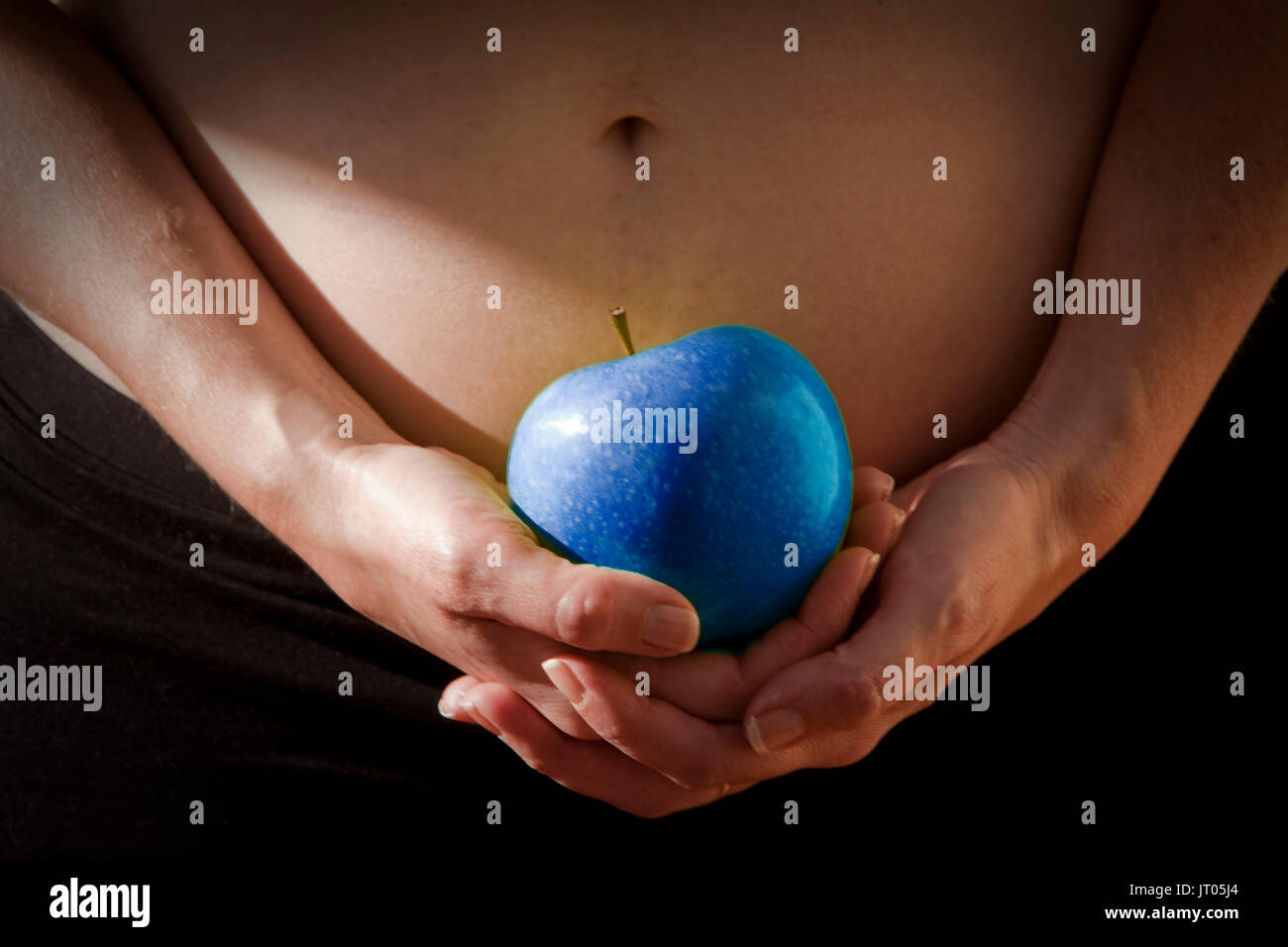 Frau mittleren Alters hält Blue Apple in ihrem Leib, Gesundheit Konzept Stockfoto