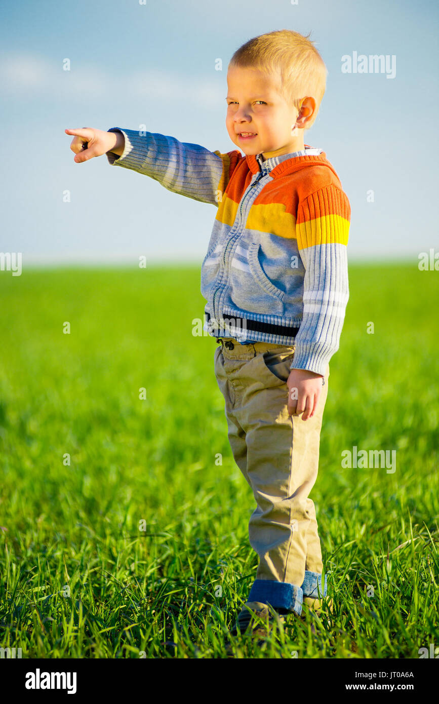 Porträt von glücklich fröhlich schönen kleinen Jungen im Freien auf Land. Weisenden Konzept. Stockfoto