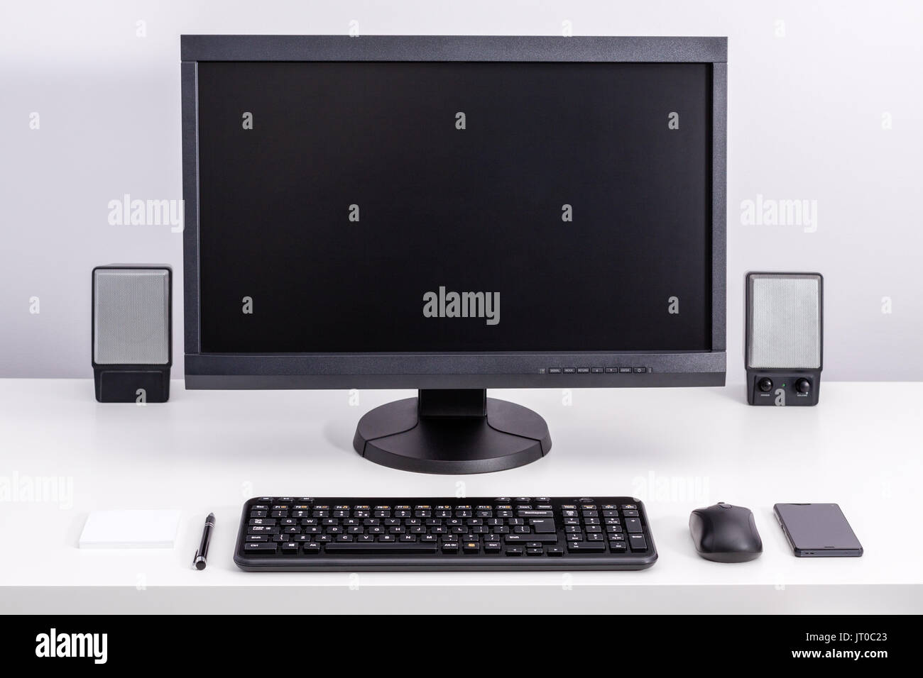 Schwarz leer PC-Monitor auf dem Schreibtisch bleiben, um bestellte Platz mit Tastatur, Maus, Smartphone, Lautsprecher, Pen und Haftnotizen. Stockfoto