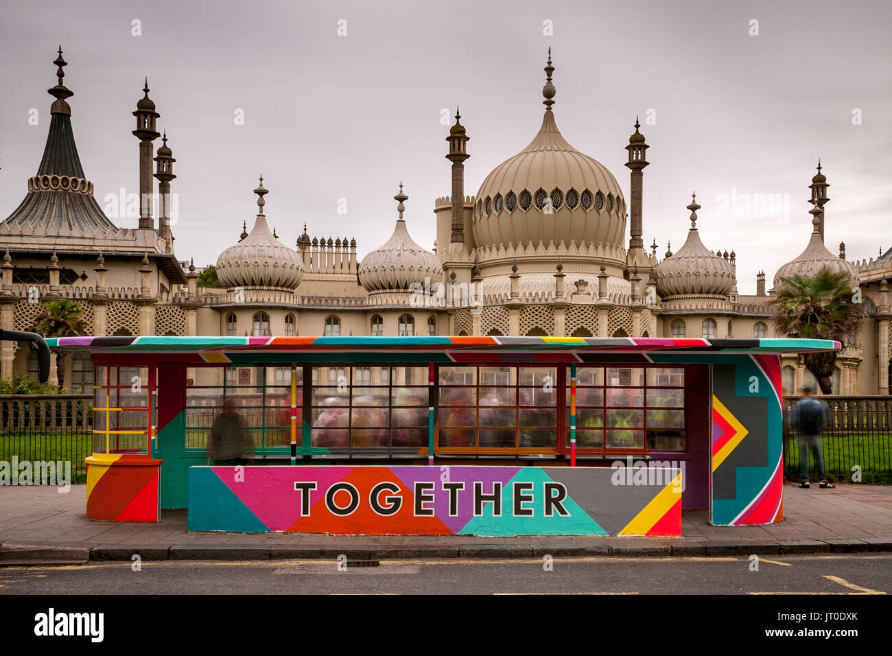 Die Menschen warten auf einen Bus in einem bunt bemalten Bus Shelter, Brighton, Sussex, UK Stockfoto