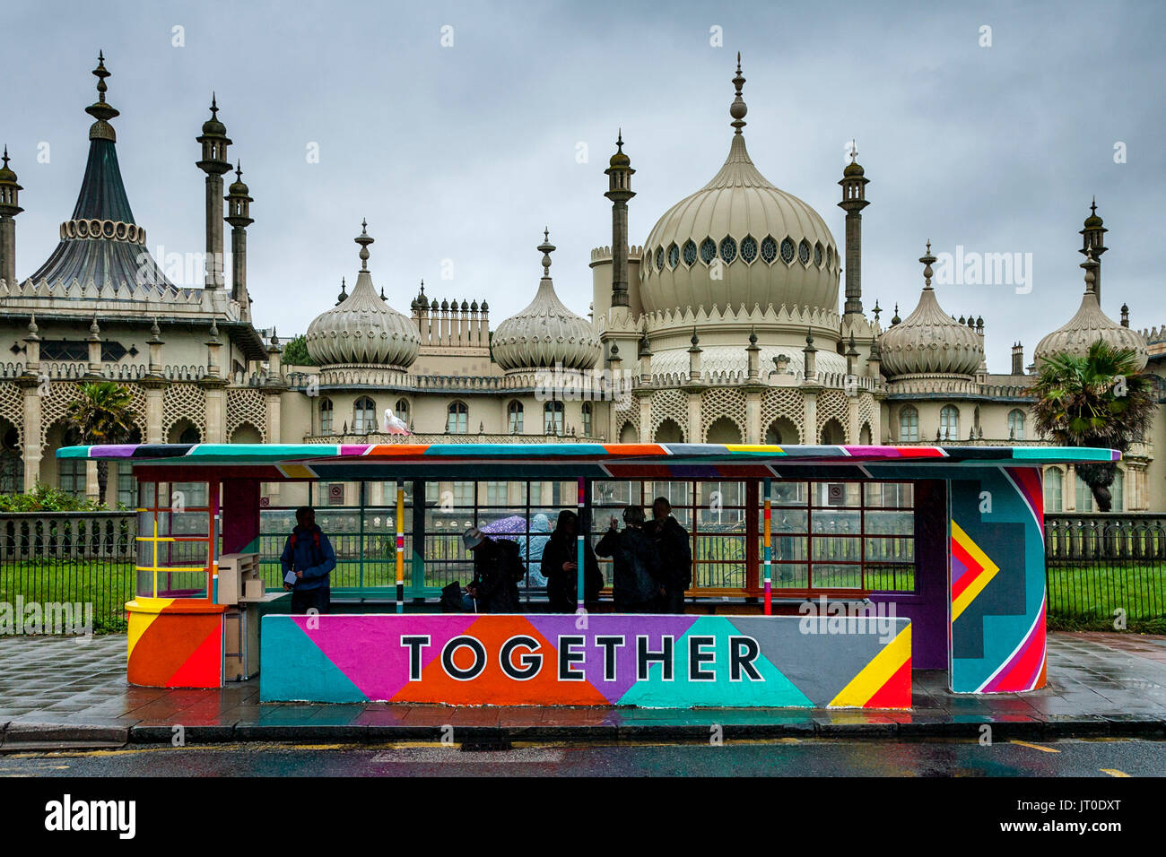 Die Menschen warten auf einen Bus in einem bunt bemalten Bus Shelter, Brighton, Sussex, UK Stockfoto