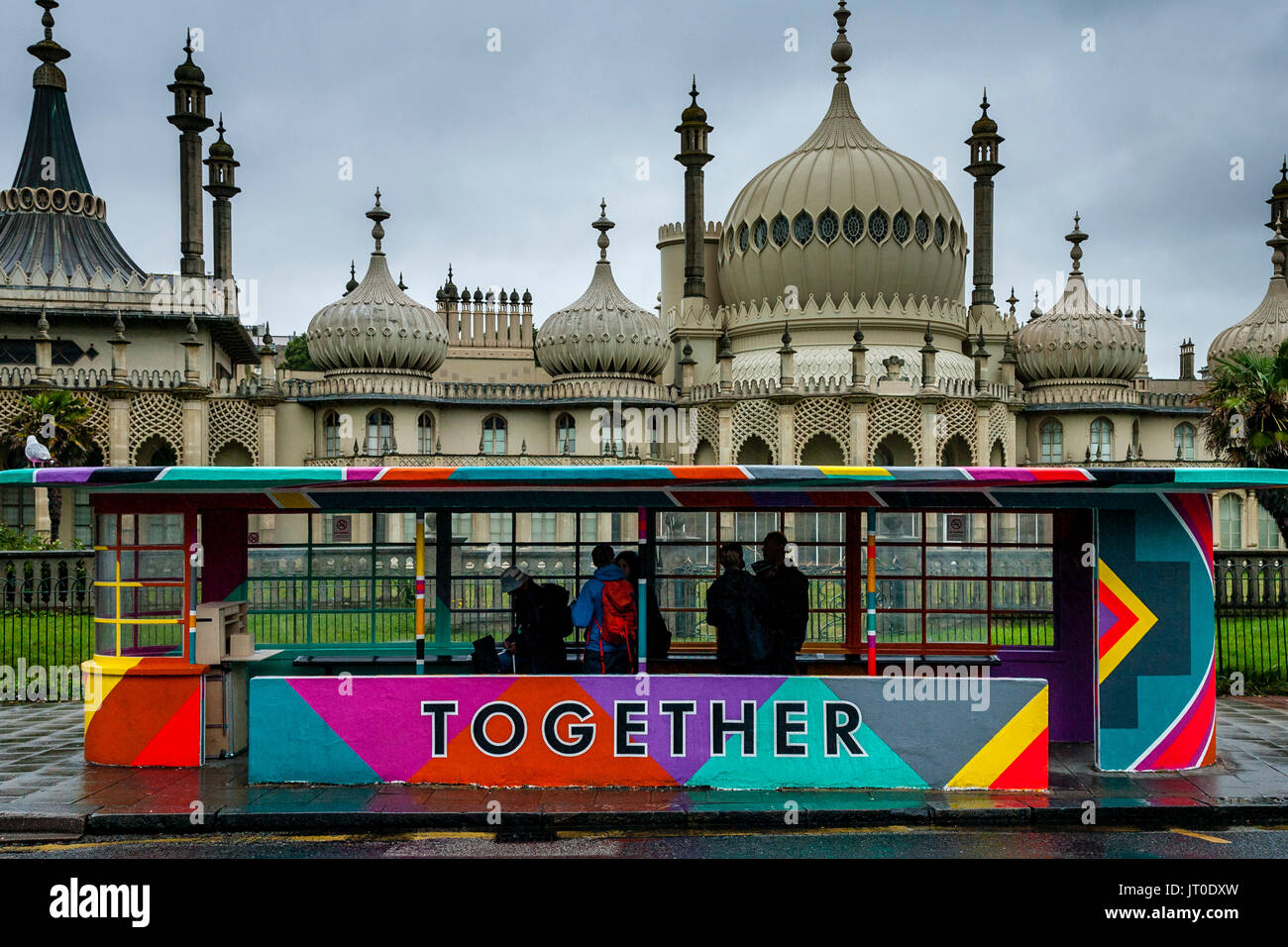 Die Menschen warten auf einen Bus in einem bunt bemalten Bus Shelter, Brighton, Sussex, UK Stockfoto