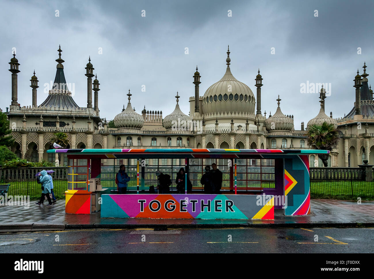Die Menschen warten auf einen Bus in einem bunt bemalten Bus Shelter, Brighton, Sussex, UK Stockfoto