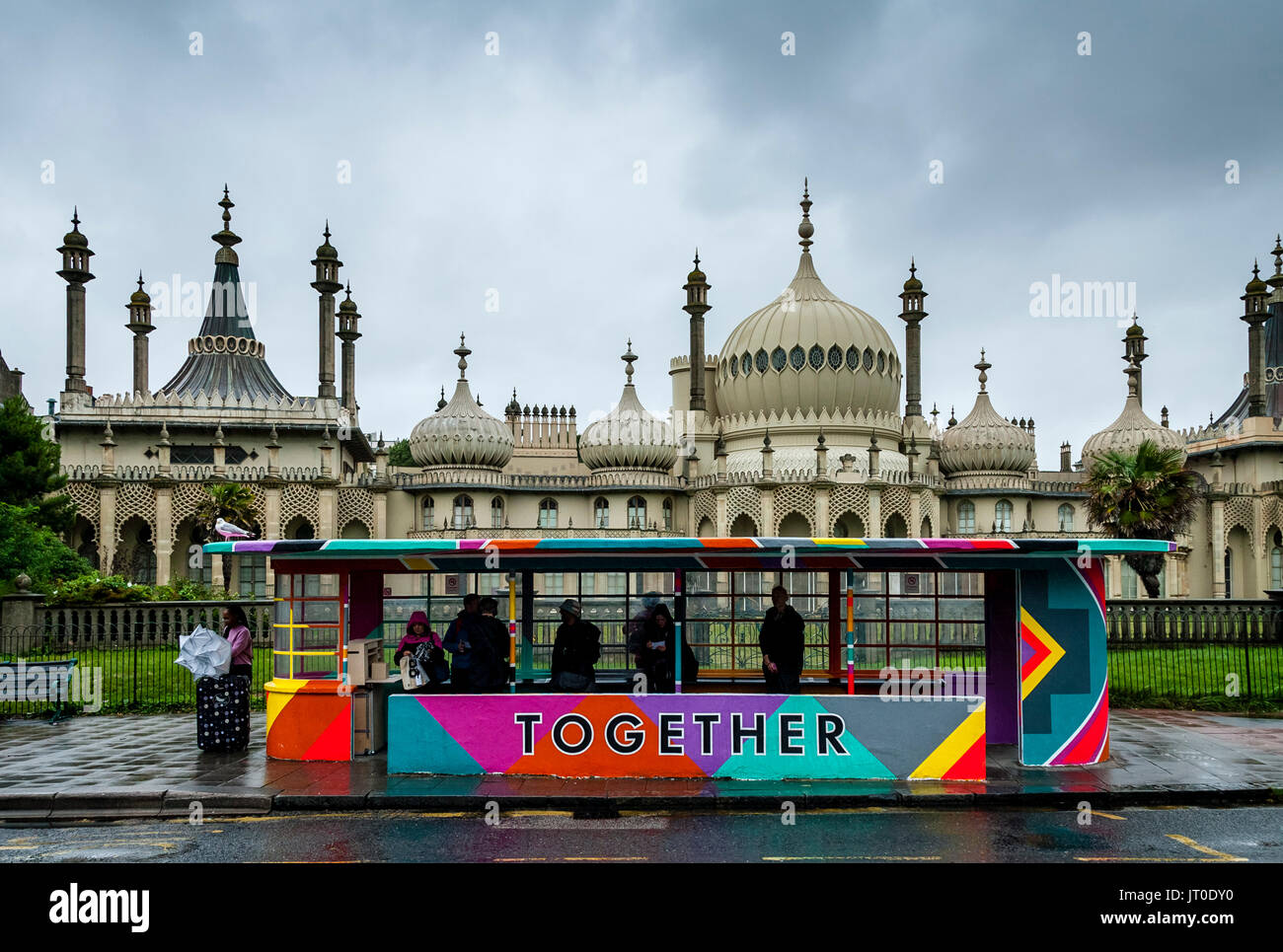 Die Menschen warten auf einen Bus in einem bunt bemalten Bus Shelter, Brighton, Sussex, UK Stockfoto