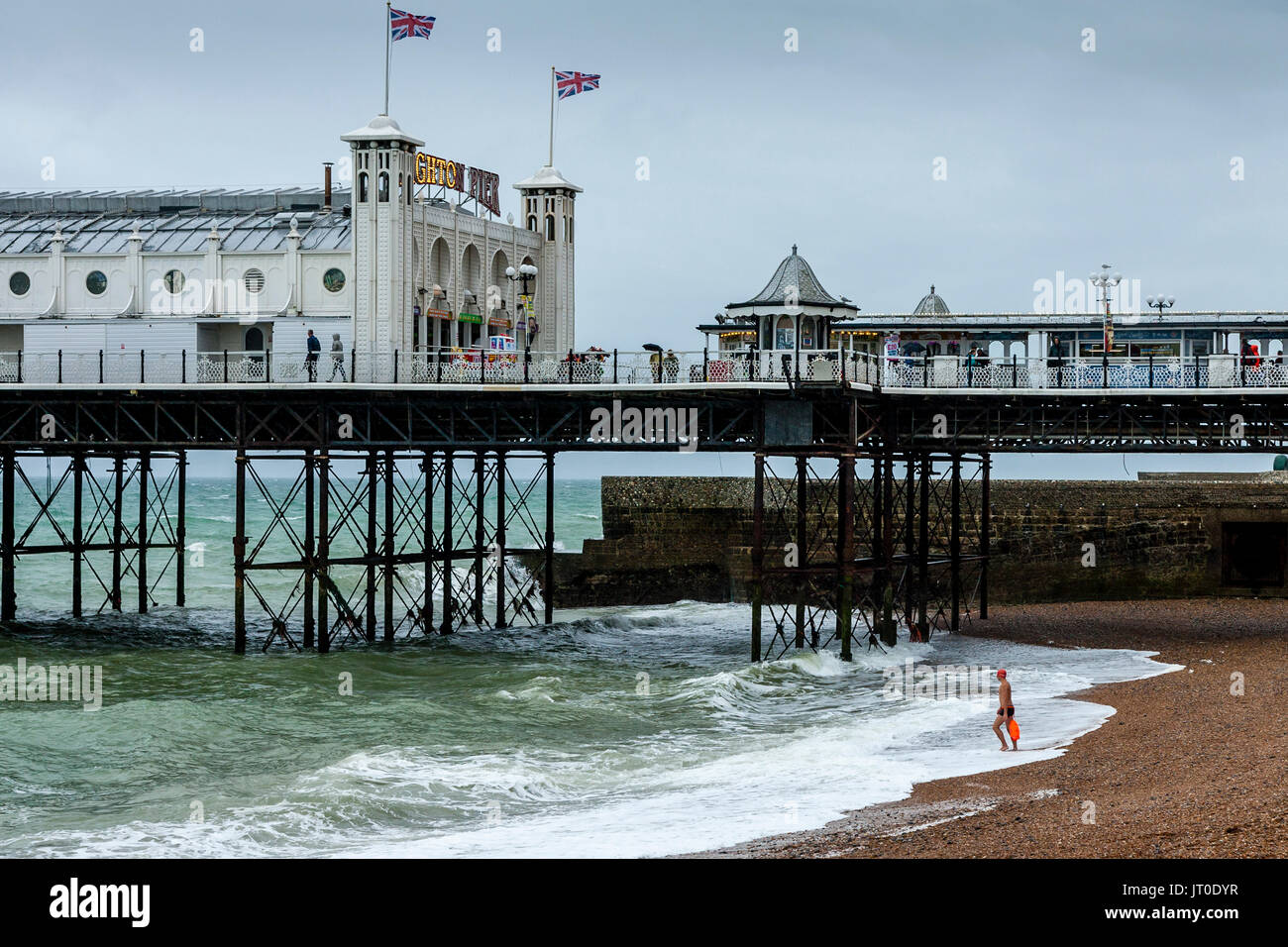 Ein Mann geht im Meer schwimmen aus Brighton Beach, Brighton, Sussex, UK Stockfoto
