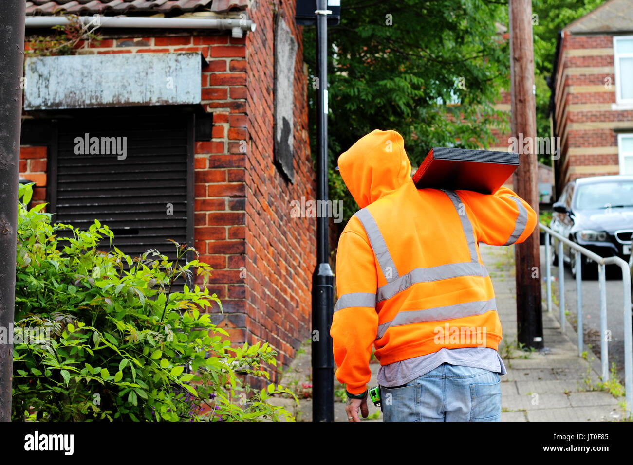 Arbeiter in der High vis Jacke trägt Blätter von Baustoffen für Eigentum Renovierung in Sheffield, Yorkshire Stockfoto