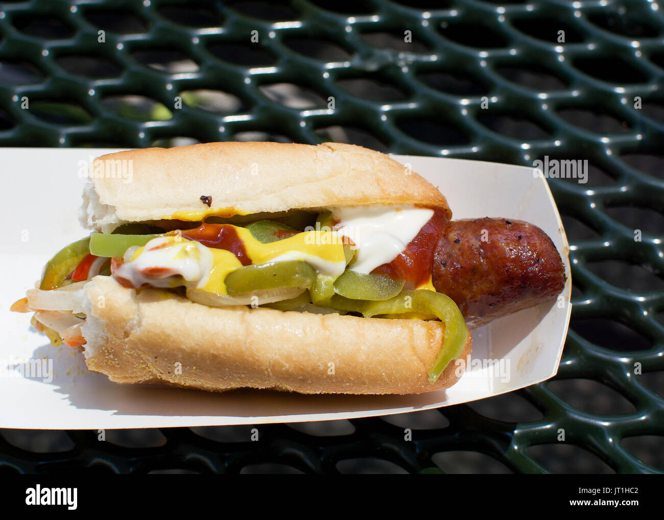 Die Hälfte gegessen Hot Dog mit Mayo, Paprika und Tomaten Sauce durchführen, auf Schwarz. Junk food Konzept. Stockfoto