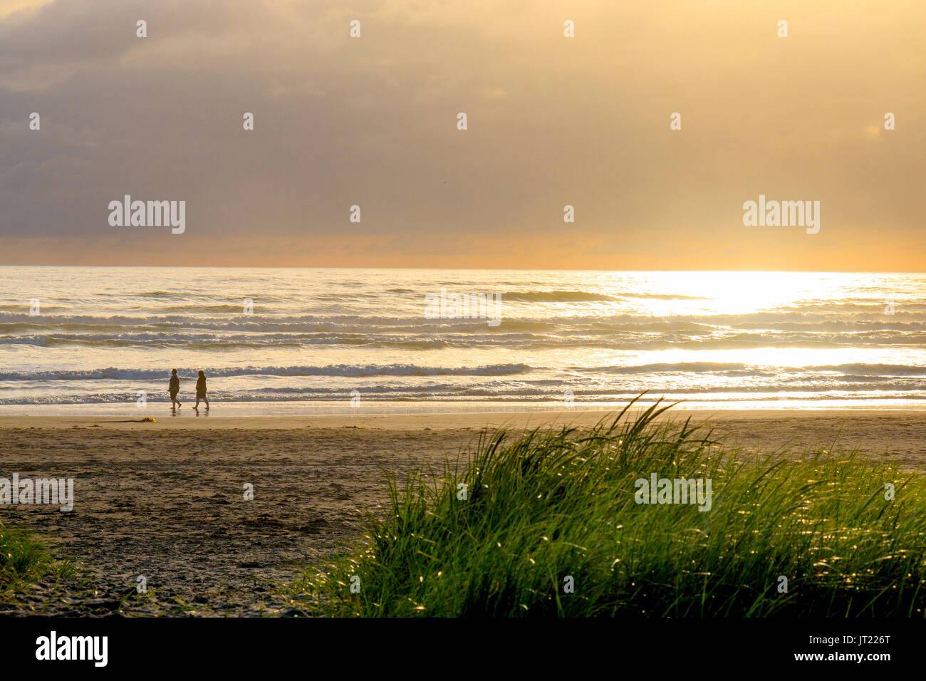 Menschen gehen am Strand von Seaside, Oregon, bei Sonnenuntergang. Stockfoto