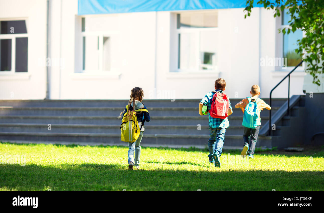 Kinder mit Rucksäcken im Park in der Nähe der Schule läuft. Schülerinnen und Schüler mit Bücher und Rucksäcke im Freien Stockfoto