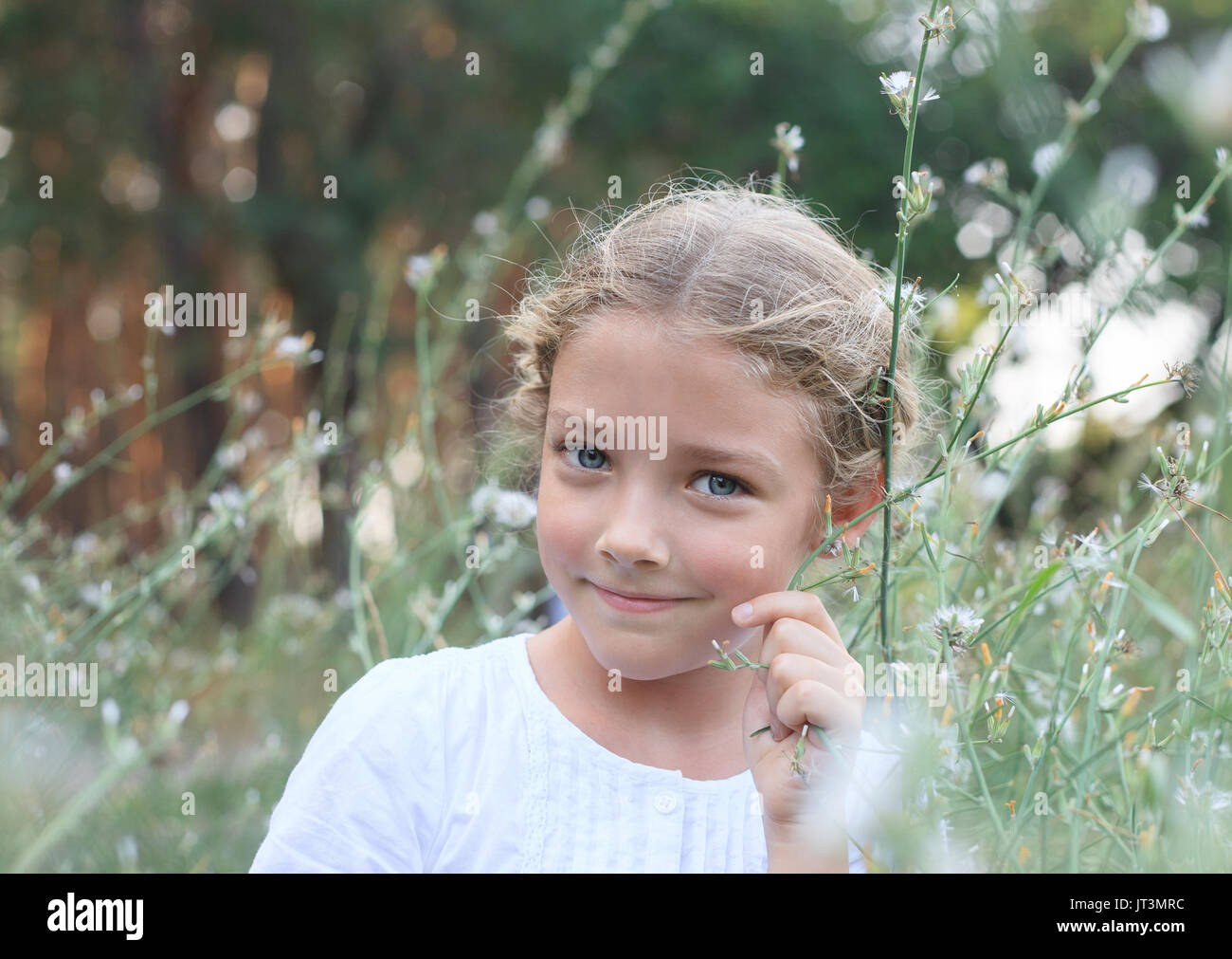 Porträt eines niedlichen kleinen Mädchen auf der Natur in den Blumen beim Gehen. Stockfoto