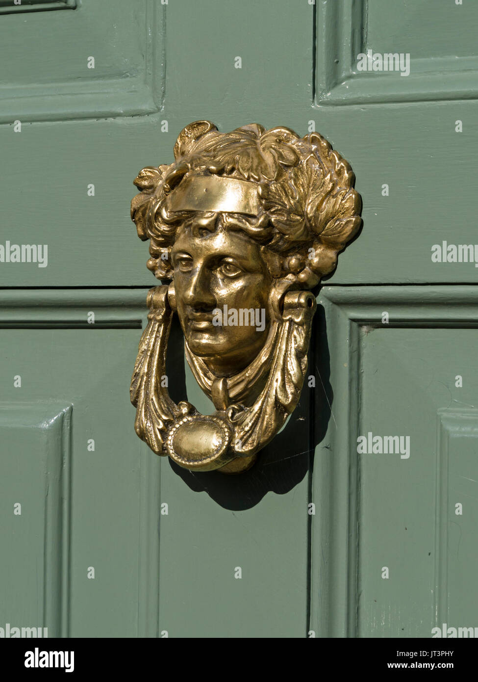 Smart golden Messing poliert Türklopfer römische Göttin Apollo, auf grünem Holz getäfelten vorderen Tür lackiert. Stockfoto