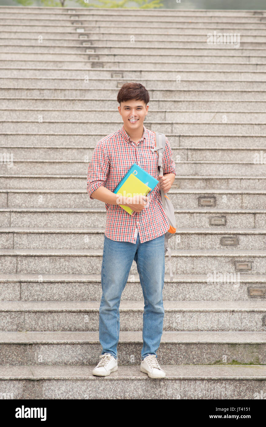 Asiatische Kursteilnehmer mit seinen Büchern und tragen Rucksack Stockfoto