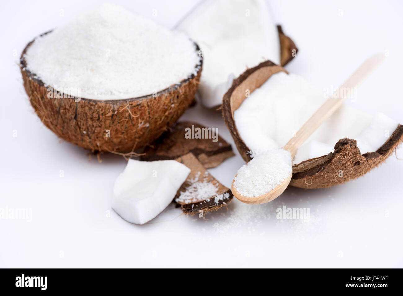 Reif organische Kokosnuss mit süßen Späne mit Holzlöffel isoliert auf weißem Stockfoto