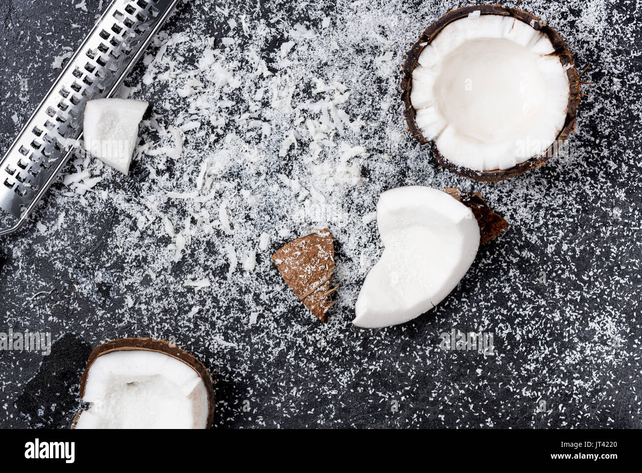 Blick von oben auf die frisch gebrochenen Kokosnuss mit Späne auf Schwarz Stockfoto