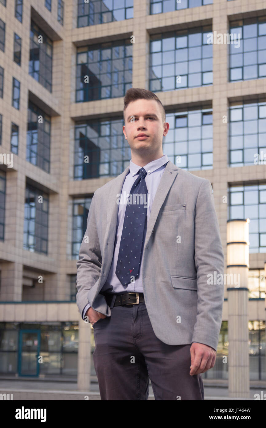 Einen jungen kaukasischen Mann, leeren Ausdruck, Hand in der Tasche, Anzug, formale Abnutzung, gewöhnliche Gemeinsame person portrait, outdoor Außen behi Stockfoto