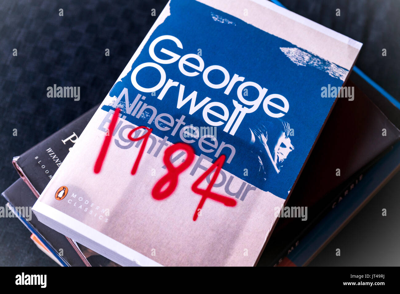 Eine Kopie des klassischen Roman "1984" von dem britischen Autor George Orwell oben auf einem Stapel Bücher Stockfoto