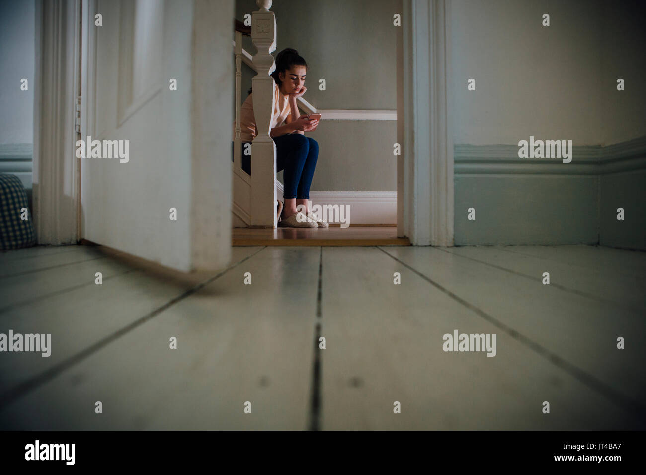 Junges Mädchen an der Unterseite einer Treppe mit einem Smartphone sitzen. Stockfoto