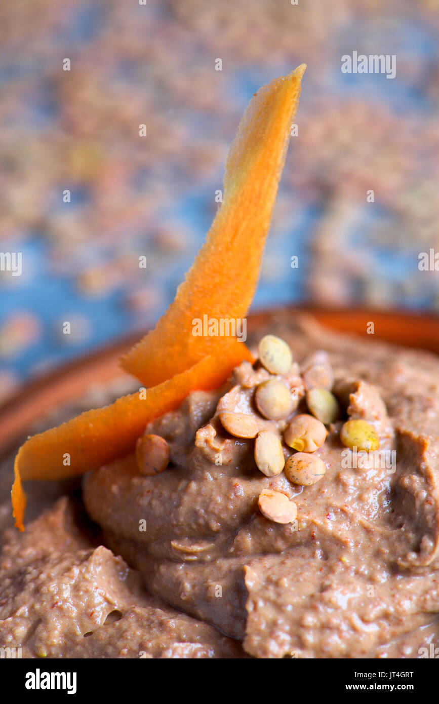 Nahaufnahme eines Steingut Schale mit appetitlichen Linse Hummus auf einem rustikalen Holztisch Stockfoto