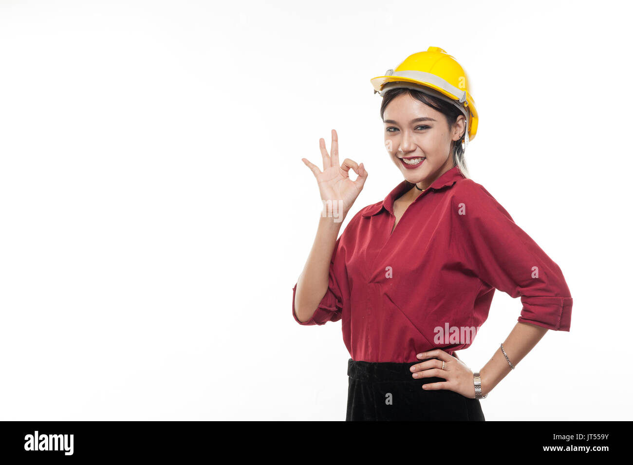 Asiatische Frau Ingenieur im roten Hemd und gelbe Schutzkappe machen Okay. Menschen gestikulieren im Geschäft und enginerring Konzept Stockfoto