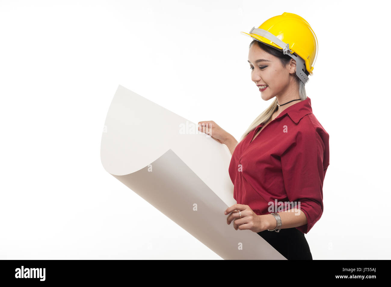 Junge asiatische Frau Architekt mit roten Hemd und gelben Helm Lächeln beim Lesen Blaupausen. industriellen Beruf Personen Konzept Stockfoto