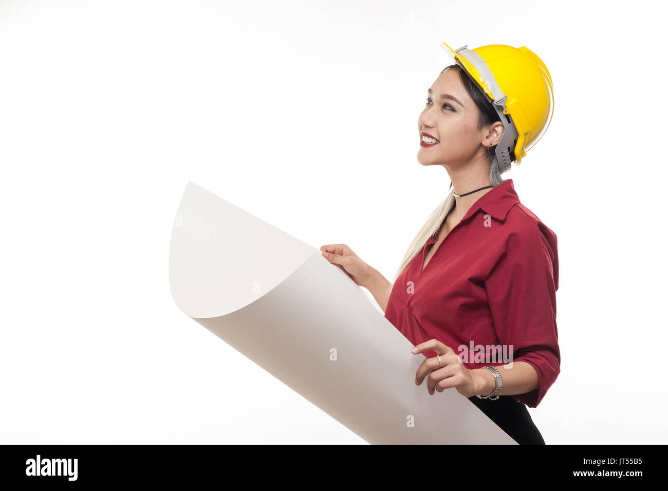 Junge asiatische Frau Architekt mit roten Hemd und gelben Helm Lächeln beim Lesen Blaupausen. industriellen Beruf Personen Konzept Stockfoto