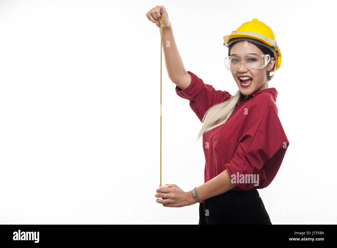 Asiatische Frau Ingenieur tragen Helm und Schutzbrille spielen mit Maßband in ihren Händen. Engineering und Industrial beruf Konzept Stockfoto