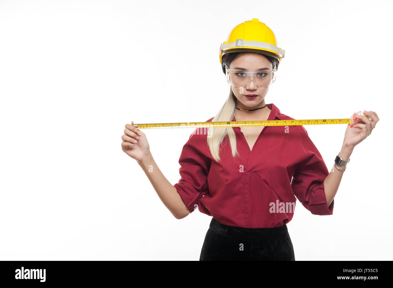Asiatische Frau Ingenieur tragen Helm und Schutzbrille spielen mit Maßband in ihren Händen. Engineering und Industrial beruf Konzept Stockfoto