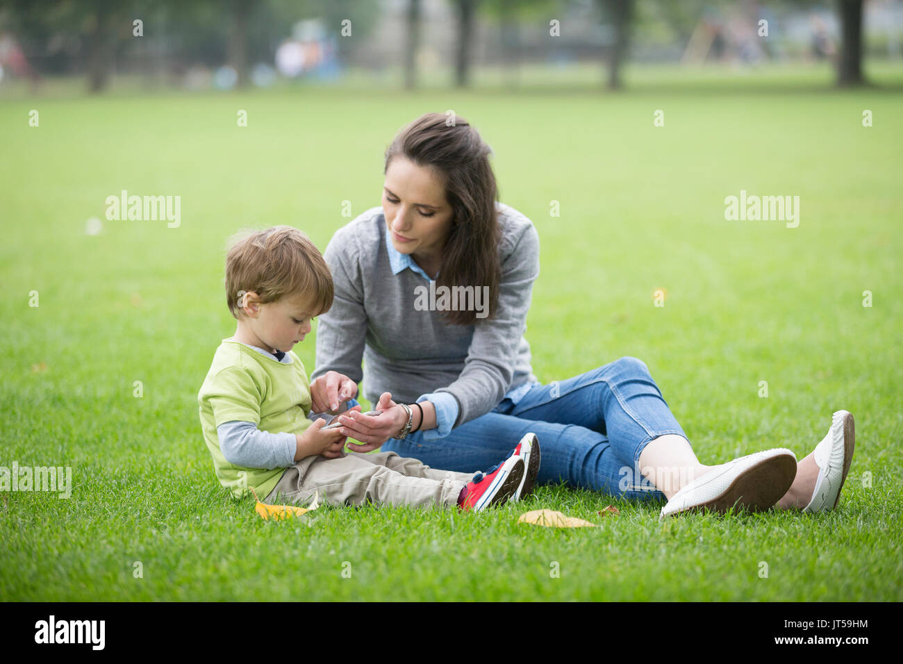 Glückliche Mutter spielt mit ihren Toddler Sohn im Freien. Liebe und Zweisamkeit Konzept. Stockfoto