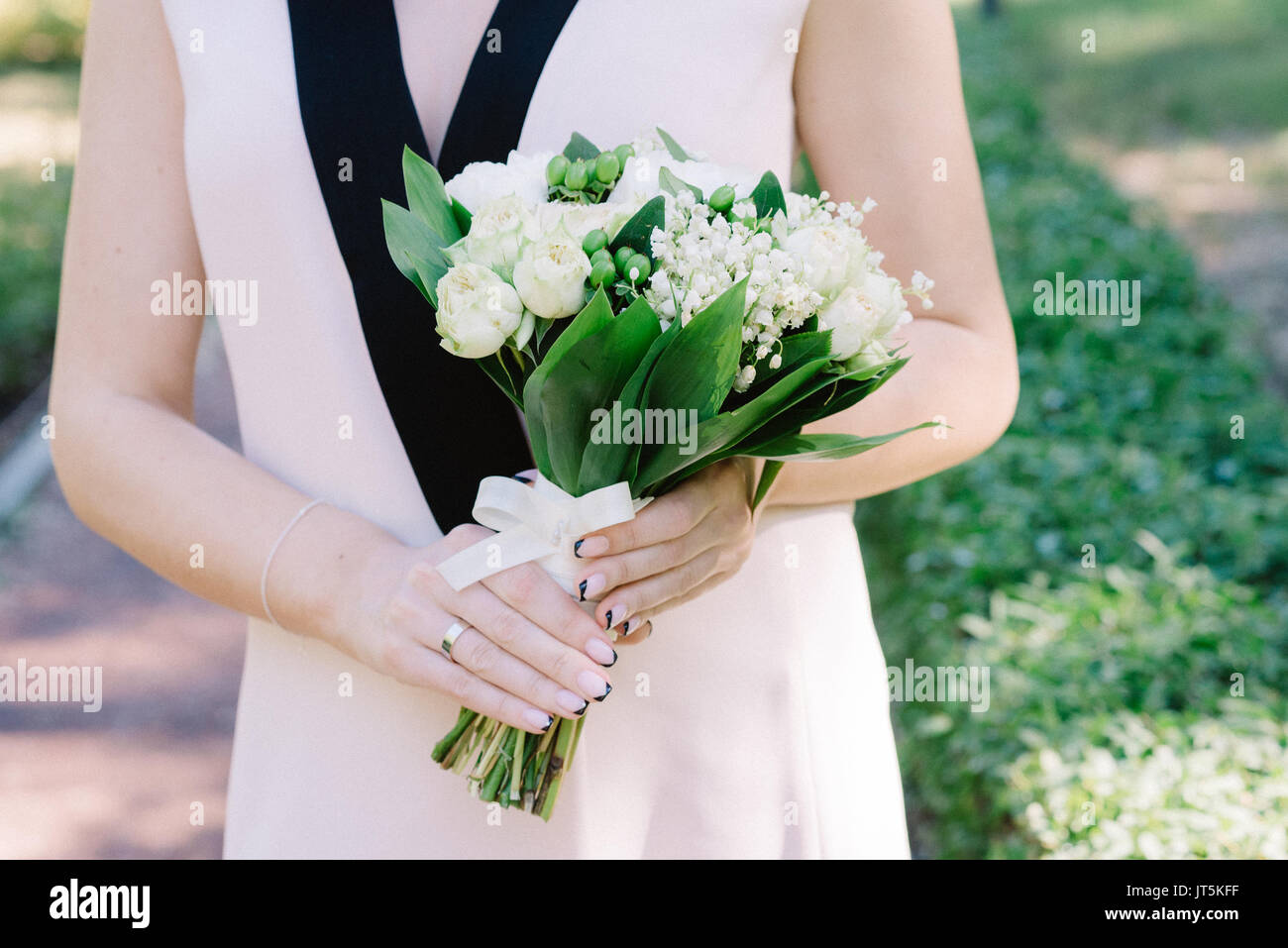 Elegante Maiglöckchen Brautstrauß in der Hand der Braut Stockfotografie