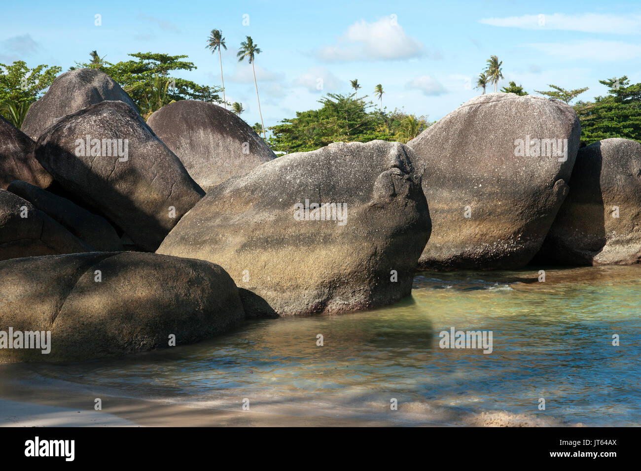 Natürliche Felsformation an der Küste von einem weißen Sandstrand mit grünen Palmen auf der Insel Belitung zurück in am Morgen, Indonesien. Stockfoto