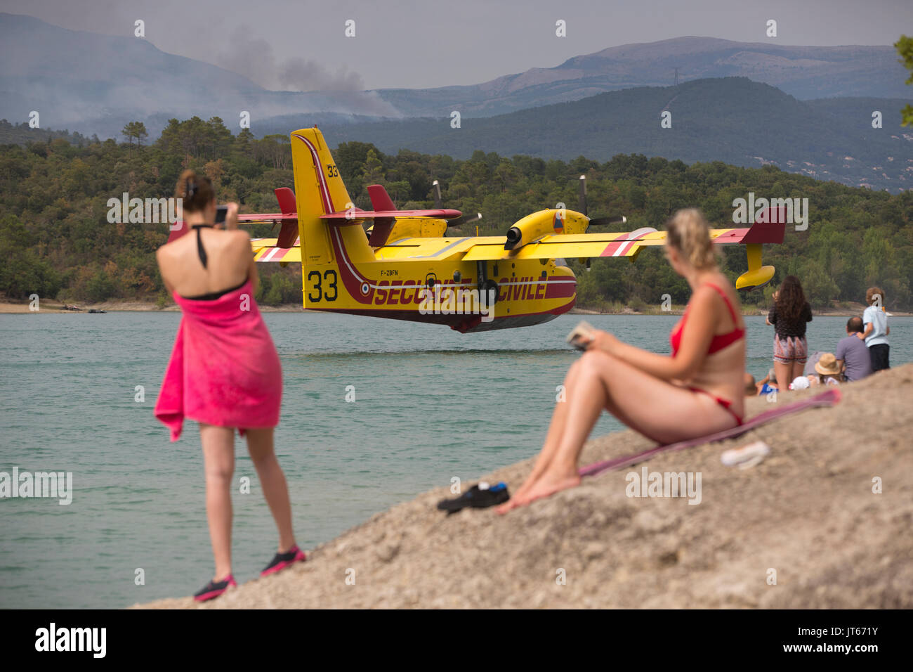 Die Badegäste beobachten Securite Civile aircarft sammeln Wasser am Lac de Saint-Cassien, Waldbrände, die in Cote d'Azur, Südfrankreich, Mittelmeer Stockfoto