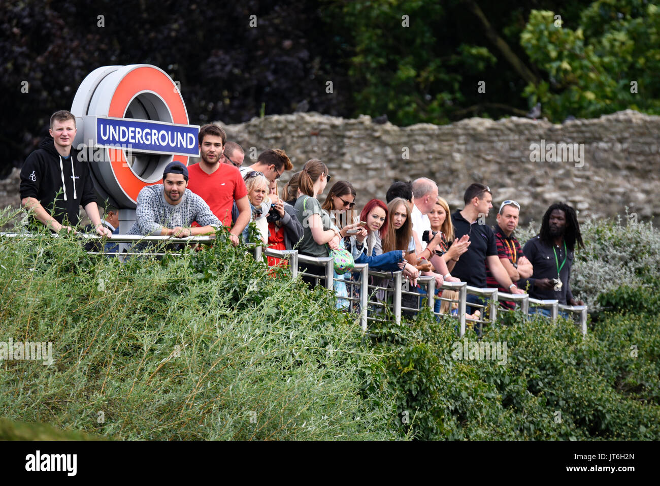 Zuschauer beobachten die Weltmeisterschaft-Marathon-Rennen von oben über dem Eingang zur U-Bahnstation Tower Hill mit Bar und Kreisschild Stockfoto