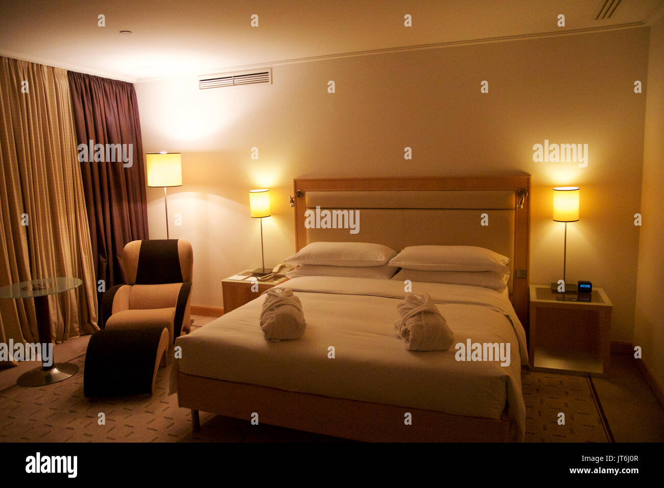 Wien, Österreich - 30. April 2017: Kingsize-Bett in einem luxuriösen Hotelzimmer mit einem Sessel in der Penthouse Suite im Hilton Vienna Stockfoto Wien, Österreich - 30. April 2017: Kingsize-Bett in einem luxuriösen Hotelzimmer mit einem Sessel in der Penthouse Suite im Hilton Vienna Stockfoto
