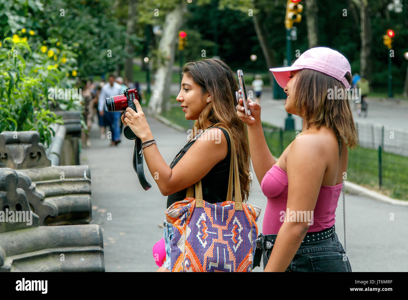 Zwei nicht identifizierte junge Damen sind, die Bilder von einem Mädchen (nicht abgebildet) im Central Park. Stockfoto