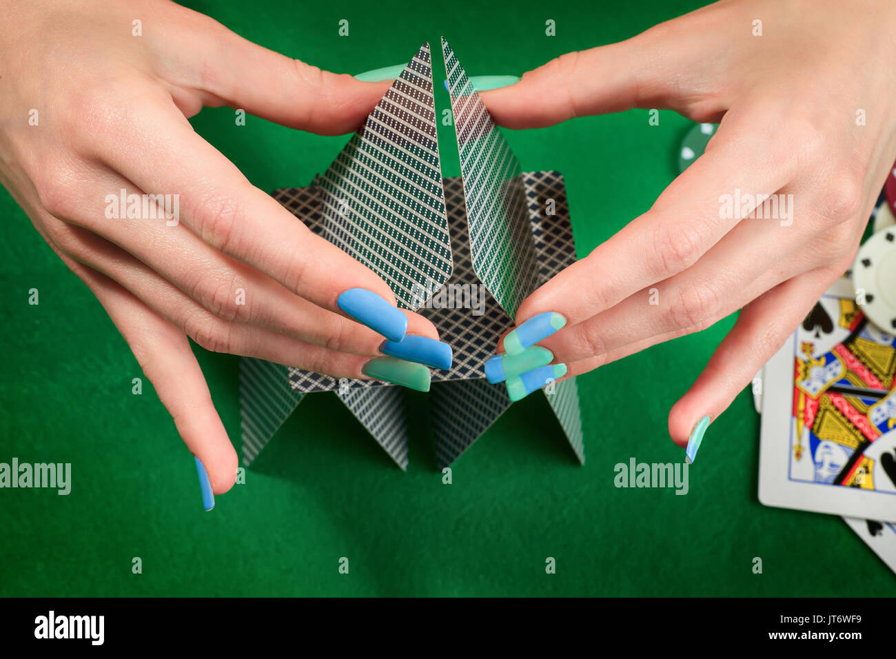 Frau Hände Montage Haus der Karten. Gegen grüne Filz Hintergrund mit Karten und poker chips. Glücksspiel und casino Thema Stockfoto