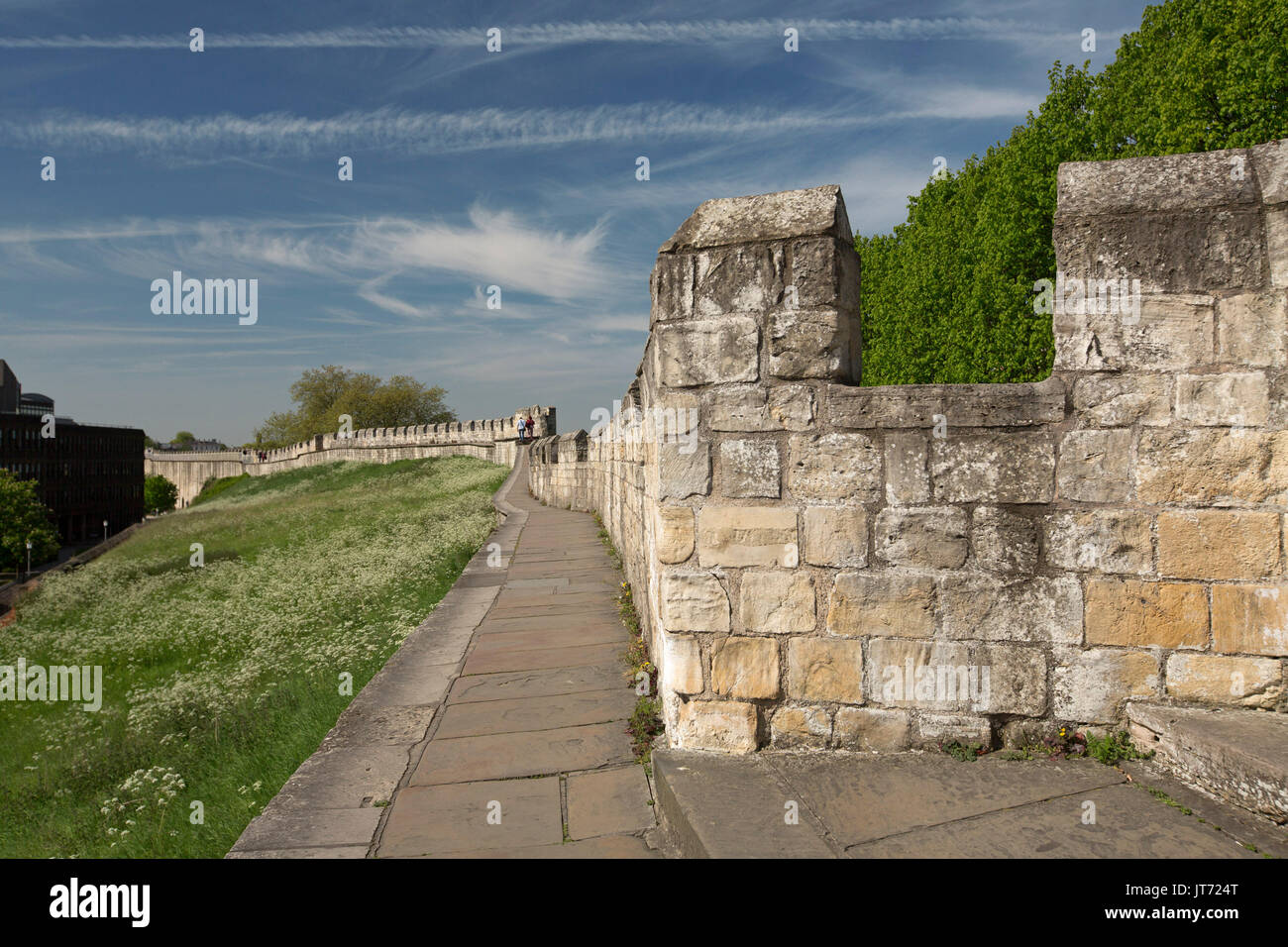 Antike römische Mauer mit Menschen in der Ferne zu Fuß auf immense Struktur unter blauem Himmel in der historischen Stadt York, England Stockfoto