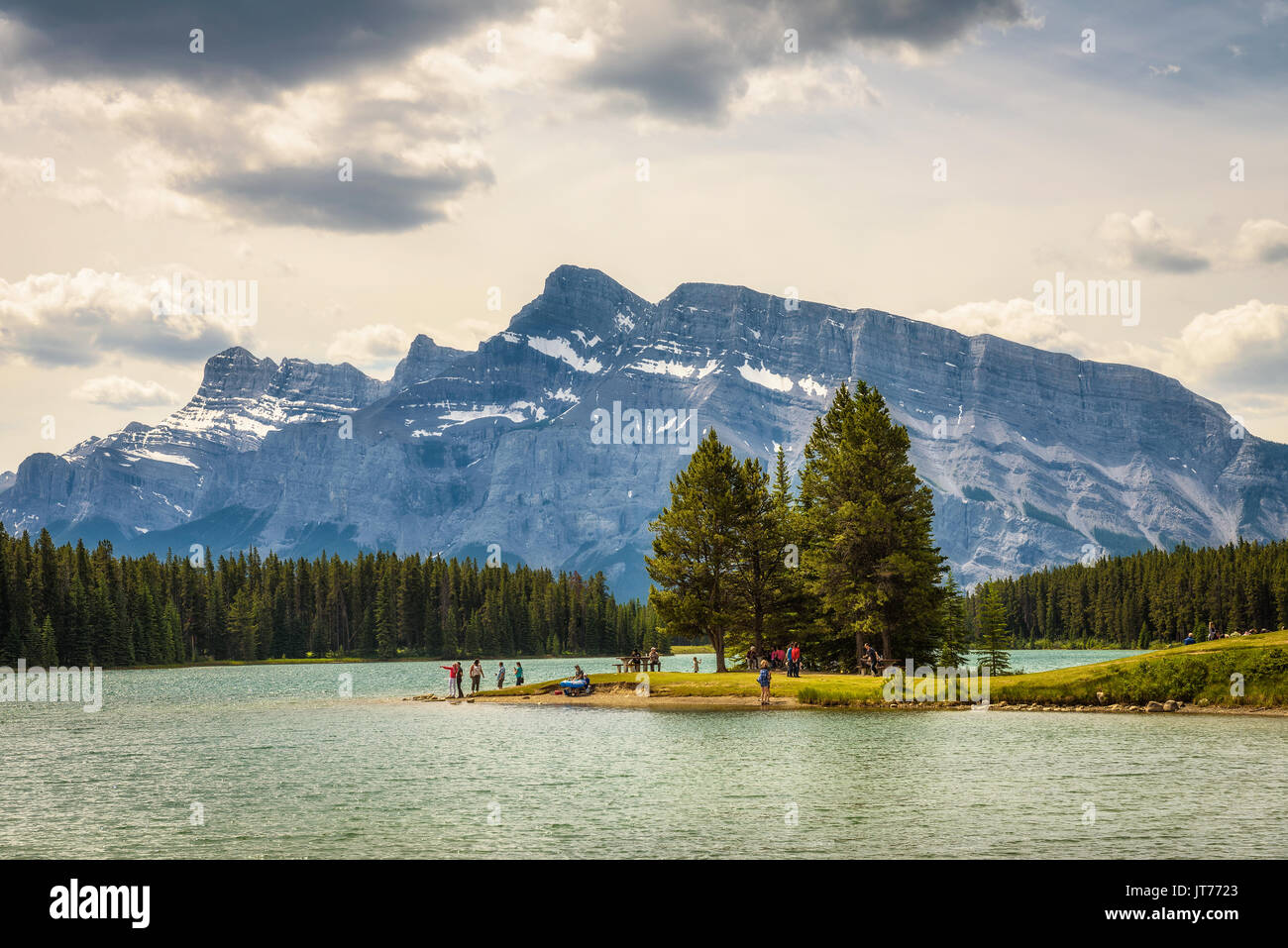 Touristen genießen einen sonnigen Tag am See im Banff National Park mit Mt. Rundle zwei Jack im Hintergrund. Stockfoto