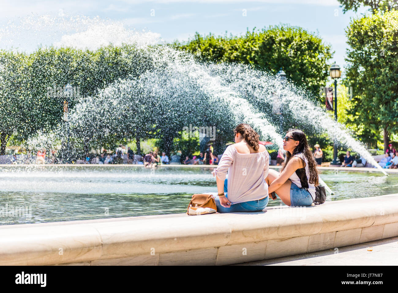 Washington DC, USA - Juli 3, 2017: Junge Mädchen Frauen sitzen auf plätschernden Springbrunnen in der skulpturengarten der Nationalgalerie im Sommer auf N Stockfoto