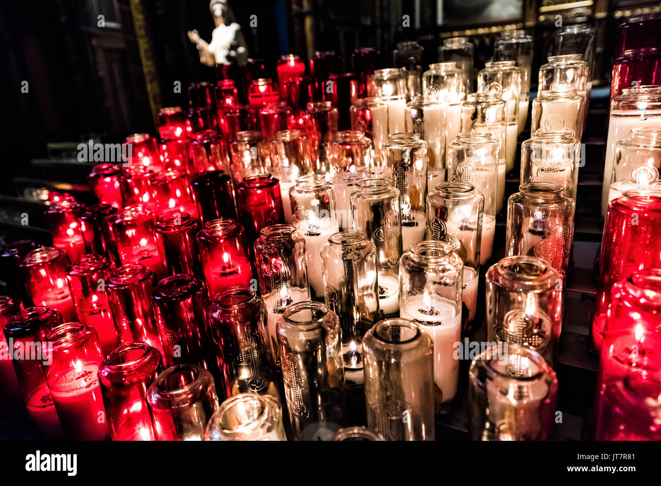 Rote und weiße Votivkerzen mit gelber Flamme in der Kirche Stockfoto