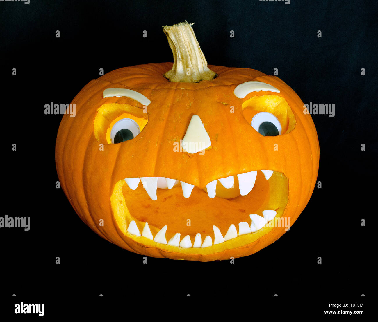 Diese scary Jack-o'-Lantern Gesicht, das geschnitten wurde in einen ausgehöhlten Kürbis mit orange Sun erweitert wurde - gebleicht weiß Seashells für Zähne, Nase, Augenbrauen, plus ein paar Kunststoff Spielzeug Augen. Carving Jack-o'-lanterns ist eine Tradition für Halloween, die von All Hallows' Eve entwickelt und setzt jährlich gefeiert werden, am 31. Oktober. Stockfoto