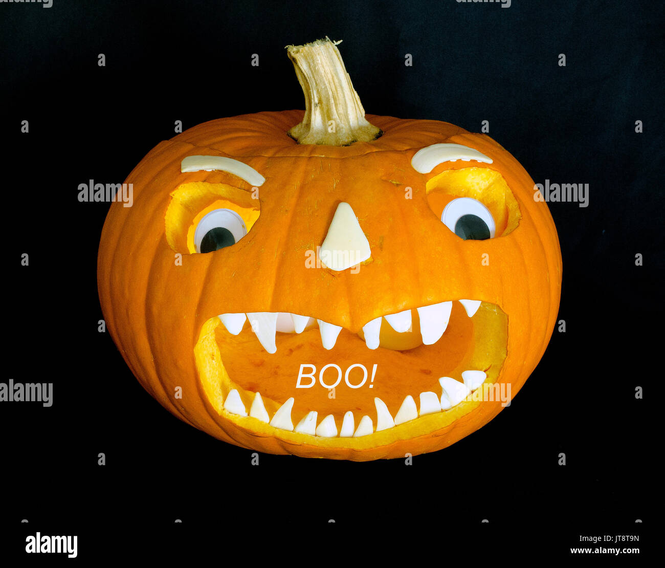 Diese scary Jack-o'-Lantern Gesicht, das geschnitten wurde in einen ausgehöhlten Kürbis mit orange Sun erweitert wurde - gebleicht weiß Seashells für Zähne, Nase, Augenbrauen, plus ein paar Kunststoff Spielzeug Augen. (Der weisse 'Buh!' wurde digital zum Bild hinzugefügt.) Carving Jack-o'-lanterns ist eine Tradition für Halloween, die von All Hallows' Eve entwickelt und setzt jährlich gefeiert werden, am 31. Oktober. Stockfoto