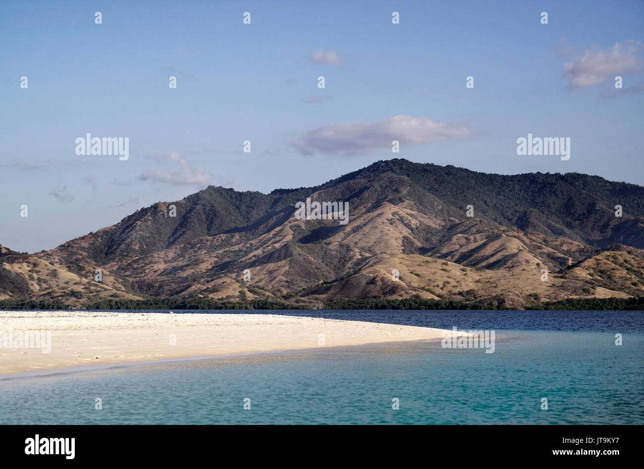 Leeren weißen Sandstrand mit blauen Ozean während des Tages mit Blick auf die Berglandschaft mit grüner Vegetation im Ozean, Flores Indonesien. Stockfoto