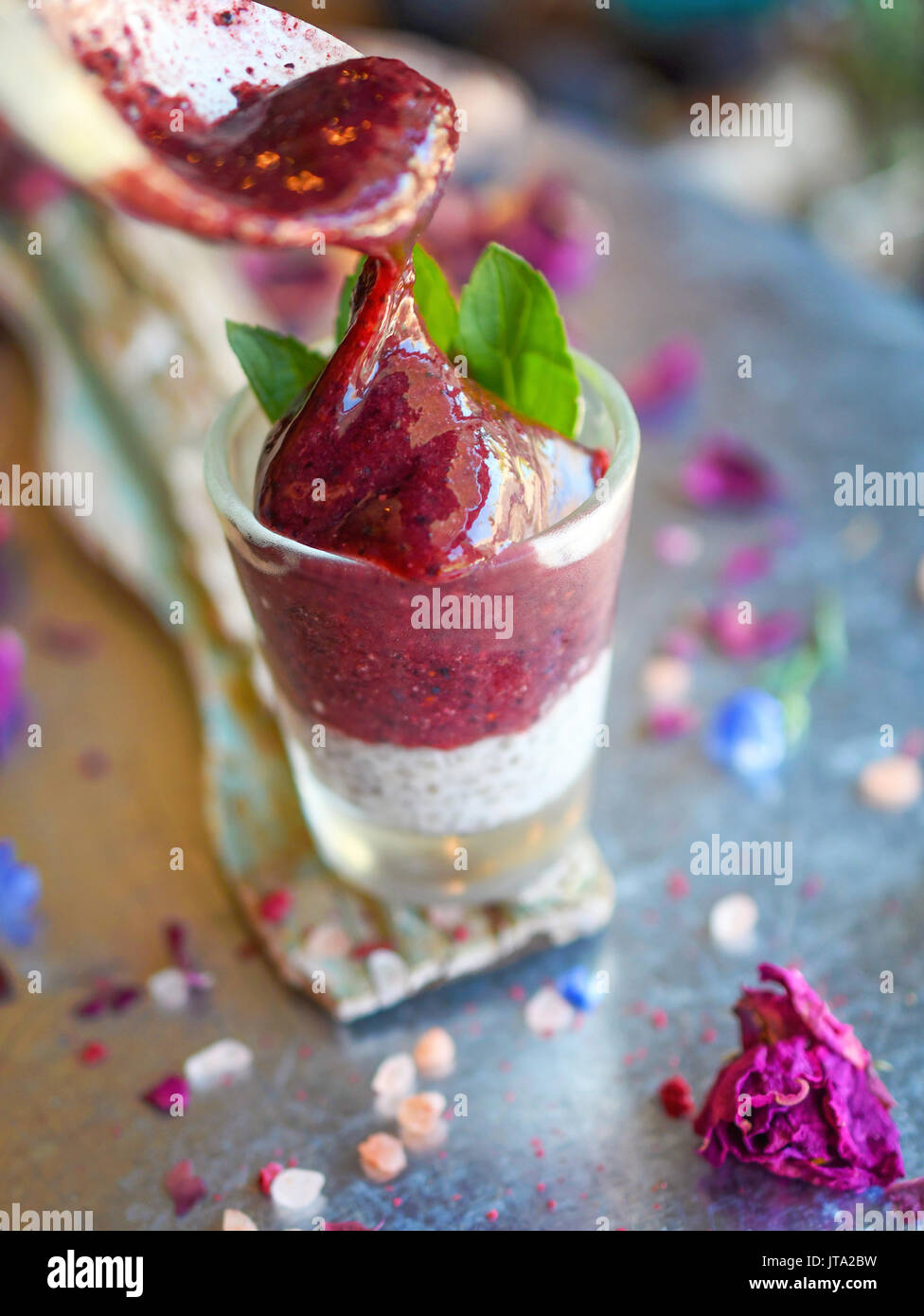 Lila smoothy mit Chia Pudding in ein Schnapsglas mit einem Zweig frische Minze auf der Oberseite für eine gesunde Glutenfreie raw vegan Schuß von Energie Stockfoto