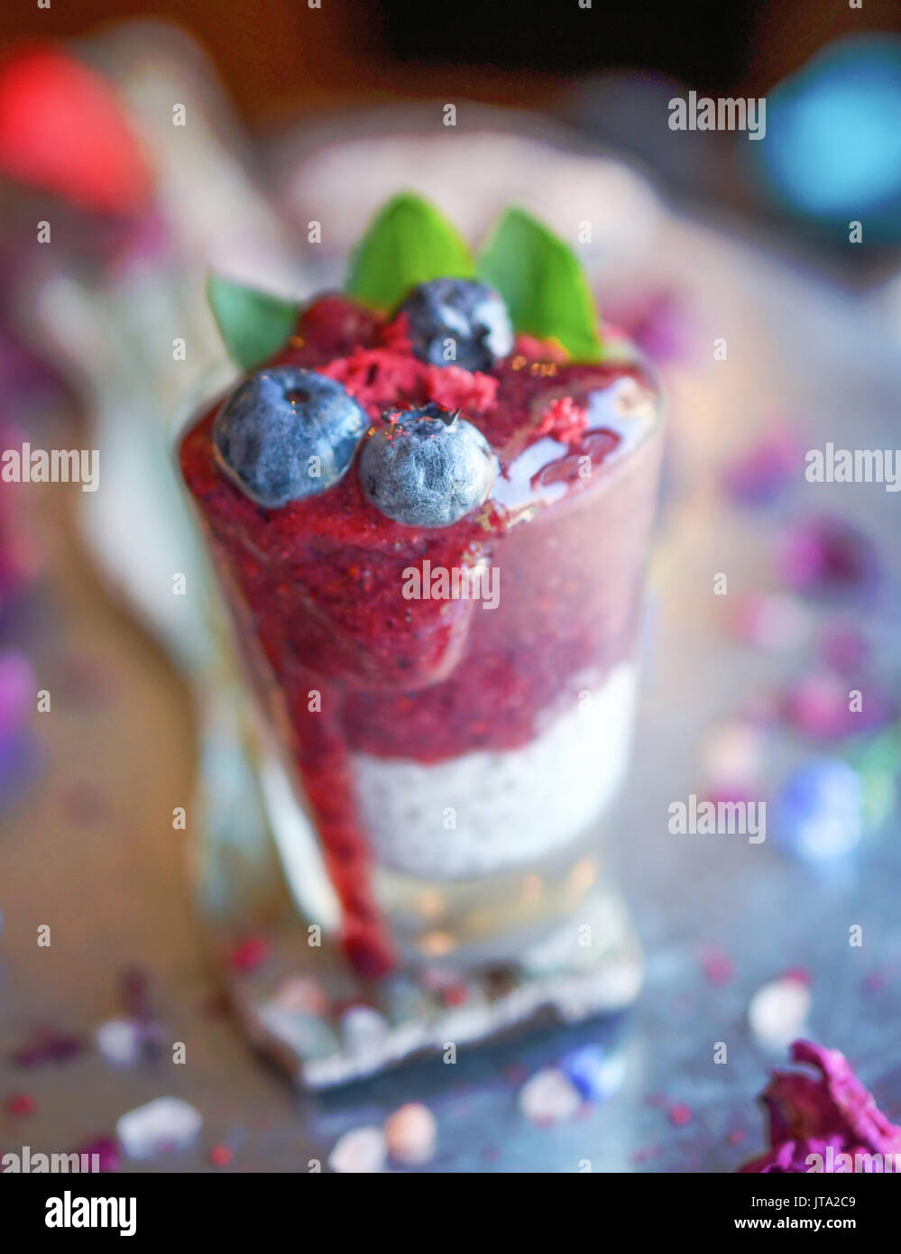 Lila smoothy mit Chia Pudding in ein Schnapsglas mit einem Zweig frische Minze auf der Oberseite für eine gesunde Glutenfreie raw vegan Schuß von Energie Stockfoto
