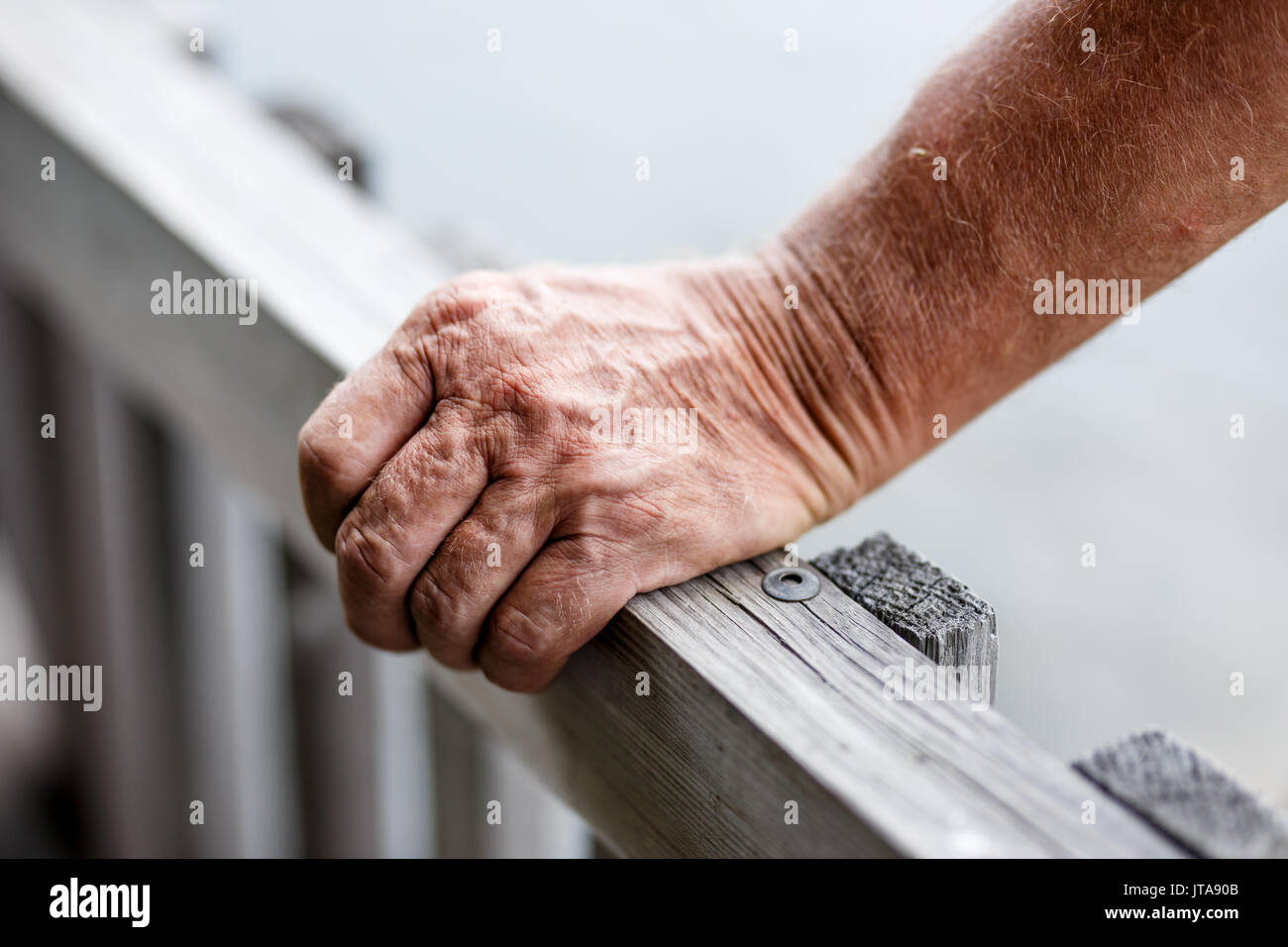 Nahaufnahme der alte Mann in der Nähe von Holzzaun beim Geländer Hand anziehen. Stockfoto